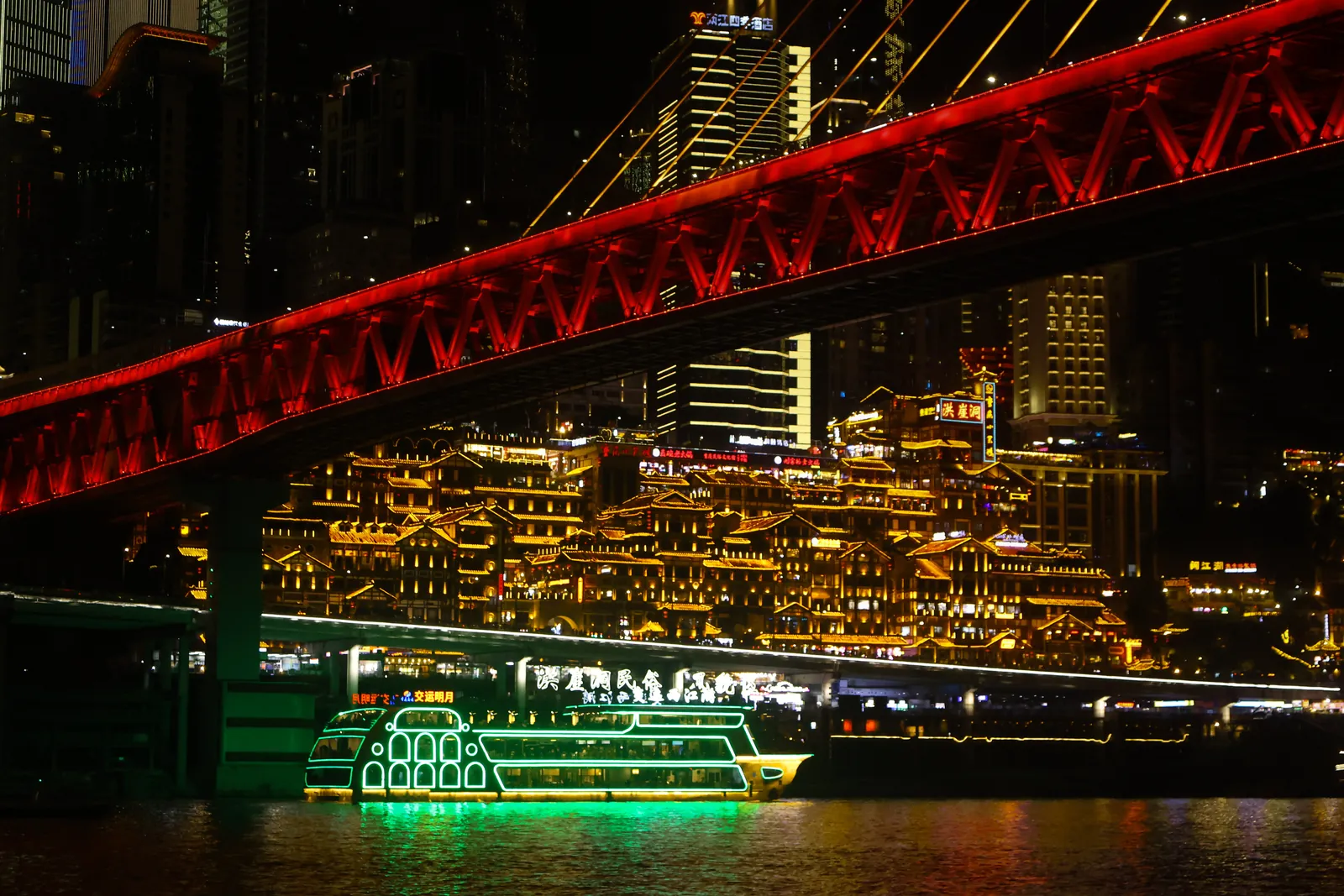 Hongyadong lit up under the red Qiansimen Bridge at night