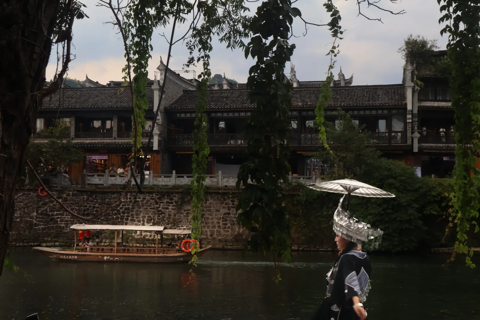 A woman in a Miao silver headdress by the river in Fenghuang