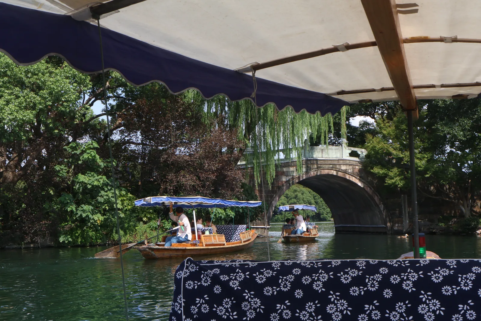 A small boat passing under a stone bridge on West Lake